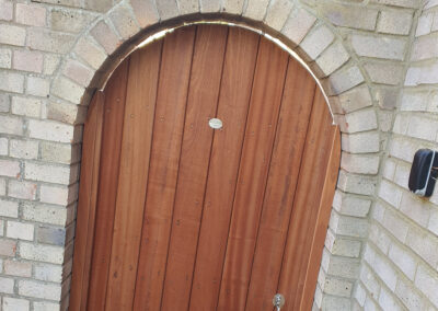 Curved wooden gate flush to curved brick work